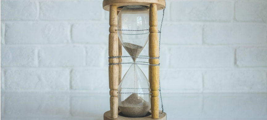 Photo of an hourglass in front of a white wall